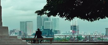 Movie still from “Layer Cake” (2004), directed by Matthew Vaughn – A man sitting on a bench looking out at a city skyline; Extreme Wide shot, Over the shoulder angle