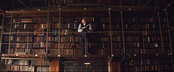 Movie still from “Layer Cake” (2004), directed by Matthew Vaughn – A man standing in front of a book shelf in a library; Wide shot, Low angle