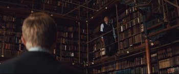 Movie still from “Layer Cake” (2004), directed by Matthew Vaughn – An older man standing in a library with a lot of books; Wide shot, High angle