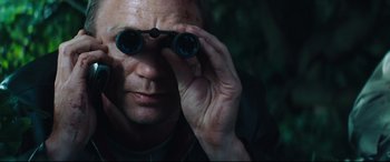 Movie still from “Layer Cake” (2004), directed by Matthew Vaughn – A man looking through a pair of binoculars; Close Up shot, Low angle