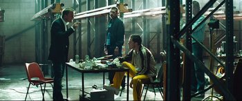 Movie still from “Layer Cake” (2004), directed by Matthew Vaughn – A group of men sitting around a table; Wide shot, Over the shoulder angle