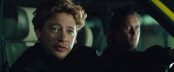 Movie still from “Layer Cake” (2004), directed by Matthew Vaughn – A person in a car looking at the camera; Close Up shot, Over the shoulder angle
