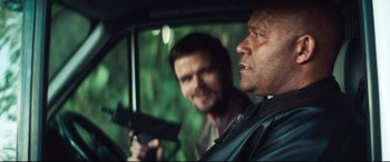 Movie still from “Layer Cake” (2004), directed by Matthew Vaughn – Two men in a car with a gun in their hand; Close Up shot, Over the shoulder angle