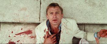Movie still from “Layer Cake” (2004), directed by Matthew Vaughn – A man in a white jacket with blood all over his face; Close Up shot, Overhead angle