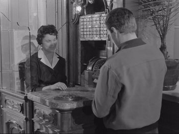 Movie still from “The Girlfriends” (1955), directed by Michelangelo Antonioni – An old photo of a man and a woman at a cash register; Medium shot, Low angle