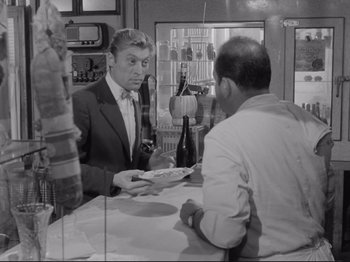 Movie still from “The Girlfriends” (1955), directed by Michelangelo Antonioni – A man in a suit is handing a plate to another man in a white shirt; Medium shot, Over the shoulder angle