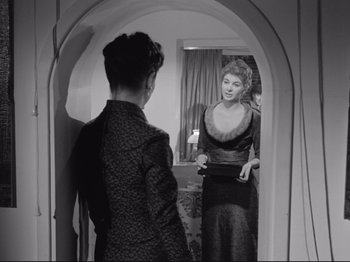 Movie still from “The Girlfriends” (1955), directed by Michelangelo Antonioni – A woman is looking in the mirror while a man looks in the mirror; Medium shot, Over the shoulder angle