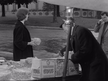 Movie still from “The Girlfriends” (1955), directed by Michelangelo Antonioni – An old photo of a man and a woman at a food stand; Medium shot, Over the shoulder angle