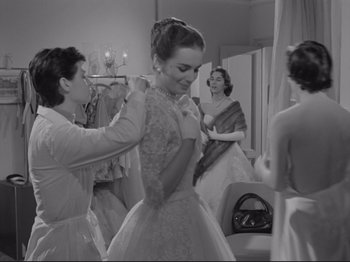 Movie still from “The Girlfriends” (1955), directed by Michelangelo Antonioni – A woman in a white dress is helping another woman put on a dress; Medium shot, Low angle