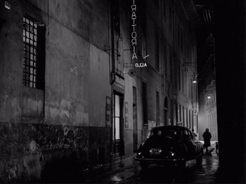 Movie still from “The Girlfriends” (1955), directed by Michelangelo Antonioni – A car parked on the side of the road in a dark city; Wide shot, Low angle
