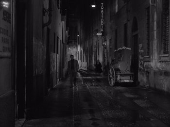 Movie still from “The Girlfriends” (1955), directed by Michelangelo Antonioni – A man walking down a street at night; Wide shot, High angle