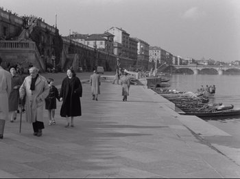 Movie still from “The Girlfriends” (1955), directed by Michelangelo Antonioni – A black and white photo of people walking along a pier; Wide shot, High angle