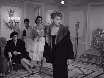 Movie still from “The Girlfriends” (1955), directed by Michelangelo Antonioni – A group of people in a room with a woman in a black dress; Medium shot, Low angle