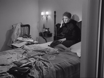 Movie still from “The Girlfriends” (1955), directed by Michelangelo Antonioni – A woman sitting on top of a bed talking on the phone; Medium shot, High angle