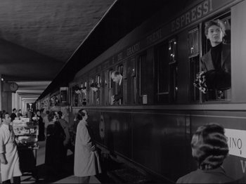 Movie still from “The Girlfriends” (1955), directed by Michelangelo Antonioni – A black - and - white photo of people standing in front of a train; Wide shot, Low angle