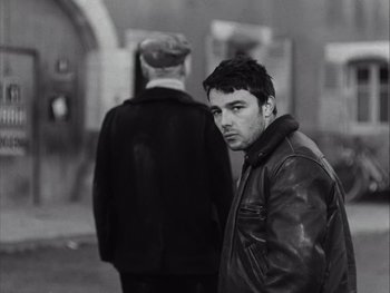 Movie still from “Le Beau Serge” (1958), directed by Claude Chabrol – A black and white photo of a man in a leather jacket; Medium shot, Over the shoulder angle