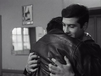 Movie still from “Le Beau Serge” (1958), directed by Claude Chabrol – Two men hugging each other in front of a window; Medium shot, Low angle