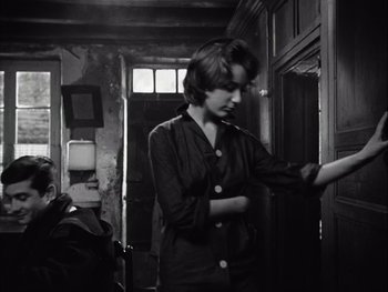 Movie still from “Le Beau Serge” (1958), directed by Claude Chabrol – A young woman standing in front of an open door; Medium shot, Over the shoulder angle