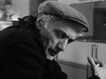 Movie still from “Le Beau Serge” (1958), directed by Claude Chabrol – An old man wearing a hat looking at a cell phone; Close Up shot, Low angle