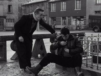 Movie still from “Le Beau Serge” (1958), directed by Claude Chabrol – Two men sitting on a park bench one of which is looking at his phone; Medium shot, High angle