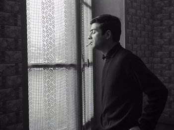Movie still from “Le Beau Serge” (1958), directed by Claude Chabrol – A man smoking a cigarette in front of a window; Close Up shot, Low angle