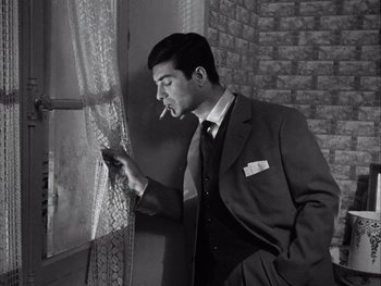 Movie still from “Le Beau Serge” (1958), directed by Claude Chabrol – A black and white photo of a man smoking a cigarette; Medium shot, Low angle