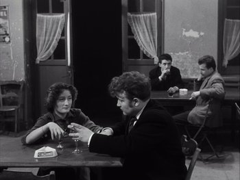 Movie still from “Le Beau Serge” (1958), directed by Claude Chabrol – A group of people sitting around a table; Medium shot, Over the shoulder angle