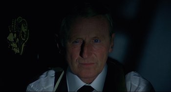 Movie still from “The Red Circle” (1970), directed by Jean-Pierre Melville – An older man wearing a vest and a tie; Close Up shot, Low angle