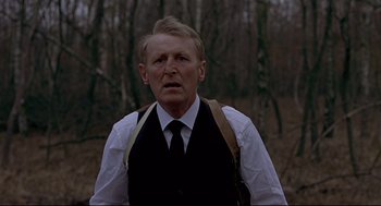 Movie still from “The Red Circle” (1970), directed by Jean-Pierre Melville – An older man wearing a vest and a tie; Close Up shot, Low angle