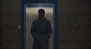 Movie still from “The Red Circle” (1970), directed by Jean-Pierre Melville – A man standing in an elevator with his hands in his pockets; Medium shot, Low angle