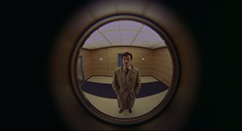 Movie still from “The Red Circle” (1970), directed by Jean-Pierre Melville – A man standing in front of a mirror in a room; Wide shot, Low angle