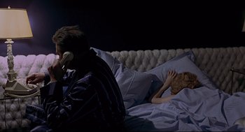 Movie still from “The Red Circle” (1970), directed by Jean-Pierre Melville – A man and a woman in a bed with a man on the phone; Medium shot, Overhead angle