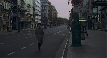 Movie still from “The Red Circle” (1970), directed by Jean-Pierre Melville – A man walking down a street near a green fire hydrant; Wide shot, High angle
