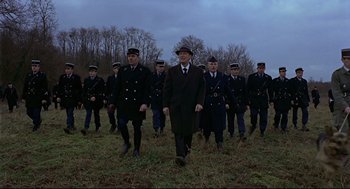Movie still from “The Red Circle” (1970), directed by Jean-Pierre Melville – A group of men in uniform walking across a field; Wide shot, High angle