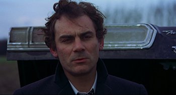 Movie still from “The Red Circle” (1970), directed by Jean-Pierre Melville – A person wearing a suit and tie; Close Up shot, Low angle