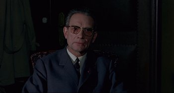 Movie still from “The Red Circle” (1970), directed by Jean-Pierre Melville – An older man wearing a suit and tie; Close Up shot, Low angle