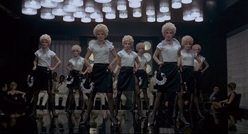 Movie still from “The Red Circle” (1970), directed by Jean-Pierre Melville – A group of women in white shirts and black skirts; Wide shot, Low angle