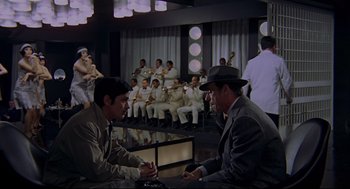 Movie still from “The Red Circle” (1970), directed by Jean-Pierre Melville – A group of men sitting in a room; Wide shot, High angle