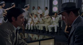 Movie still from “The Red Circle” (1970), directed by Jean-Pierre Melville – A group of men in white suits sitting around a table; Medium shot, Over the shoulder angle