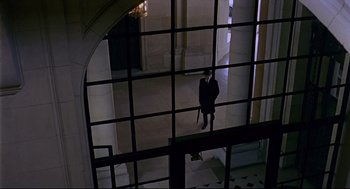 Movie still from “The Red Circle” (1970), directed by Jean-Pierre Melville – A man in a suit sitting in front of a window in a building; Extreme Wide shot, High angle