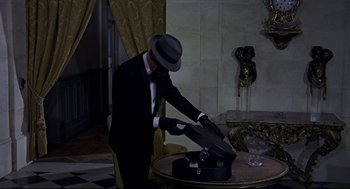 Movie still from “The Red Circle” (1970), directed by Jean-Pierre Melville – A man in a black suit and a black hat; Medium shot, High angle