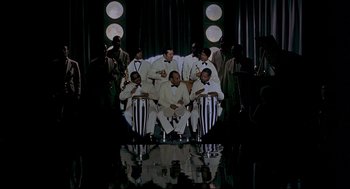 Movie still from “The Red Circle” (1970), directed by Jean-Pierre Melville – A group of men sitting on top of drums; Extreme Wide shot, High angle