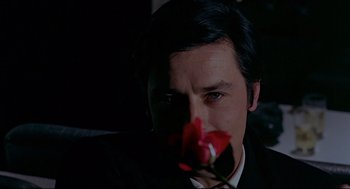 Movie still from “The Red Circle” (1970), directed by Jean-Pierre Melville – A person holding a rose; Close Up shot, Over the shoulder angle