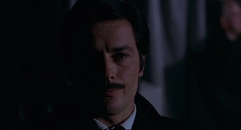 Movie still from “The Red Circle” (1970), directed by Jean-Pierre Melville – A person wearing a suit and tie; Close Up shot, Low angle