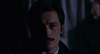 Movie still from “The Red Circle” (1970), directed by Jean-Pierre Melville – A person wearing a suit and tie; Close Up shot, Low angle