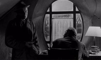 Movie still from “Le Doulos” (1962), directed by Jean-Pierre Melville – A man and a woman sitting in front of an open window; Medium shot, Over the shoulder angle