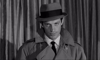 Movie still from “Le Doulos” (1962), directed by Jean-Pierre Melville – A black and white photo of a man wearing a hat and coat; Close Up shot, Low angle