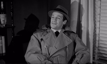 Movie still from “Le Doulos” (1962), directed by Jean-Pierre Melville – A black and white photo of a man wearing a hat and coat; Medium shot, Low angle