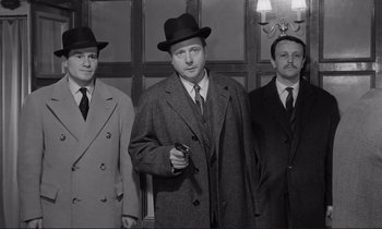 Movie still from “Le Doulos” (1962), directed by Jean-Pierre Melville – A group of men standing next to each other in suits; Medium shot, Low angle