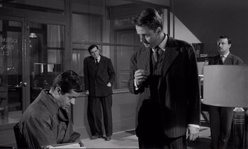 Movie still from “Le Doulos” (1962), directed by Jean-Pierre Melville – A group of men standing next to each other in a room; Medium shot, Over the shoulder angle